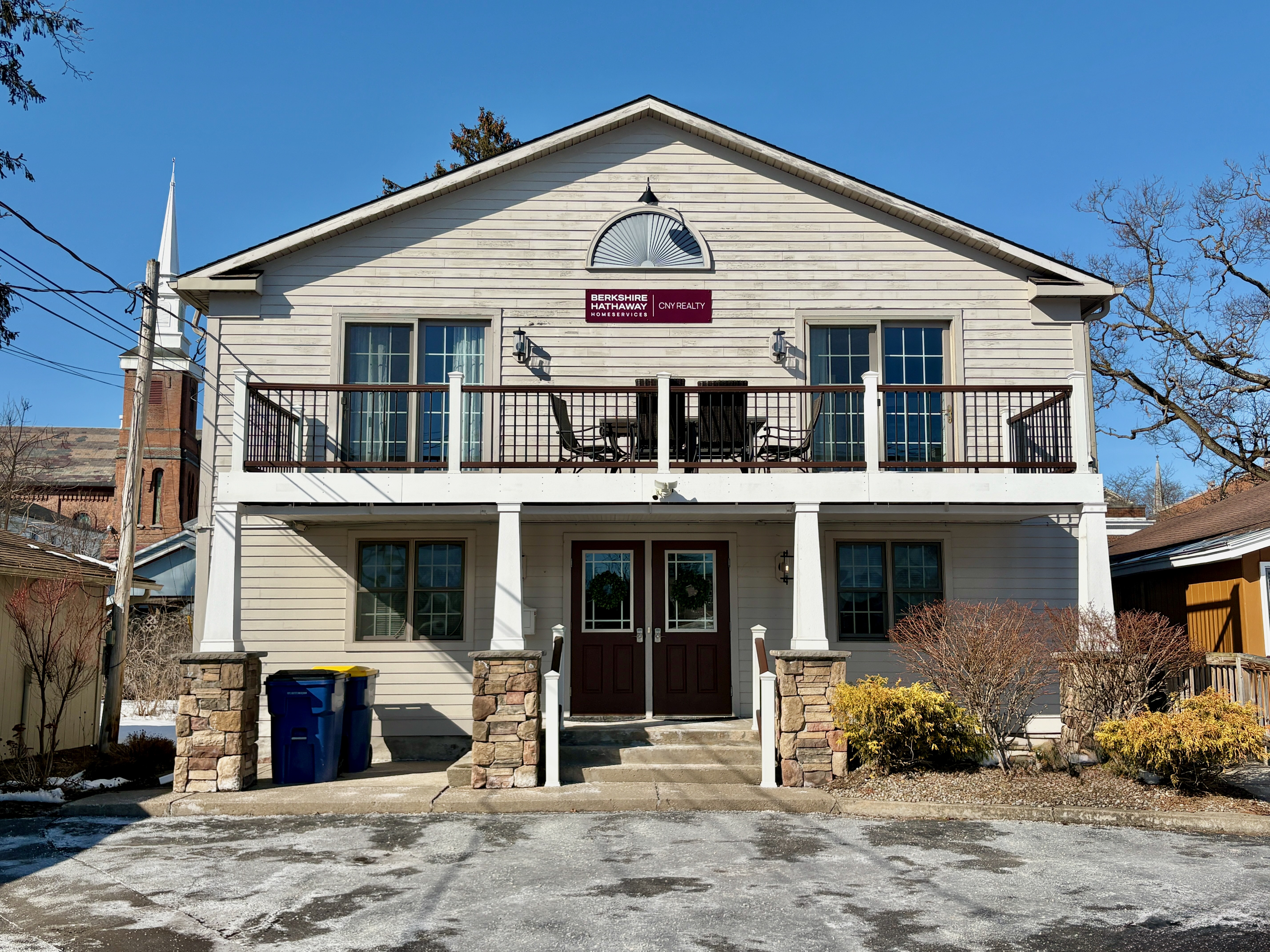 Tan office building with a second-floor deck and pillars underneath