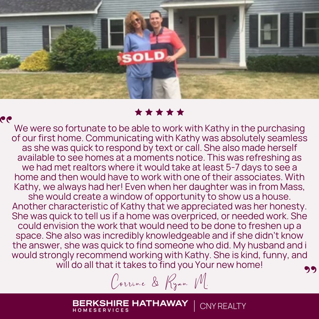 Two people in front of a blue house holding a sign that says "sold"