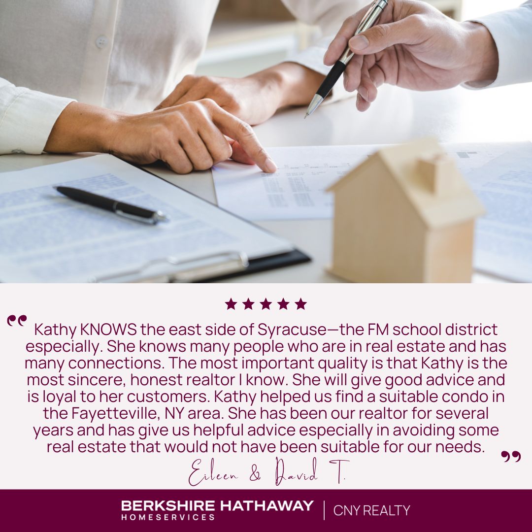 A close up of two people signing real estate documents with a small model of a home.